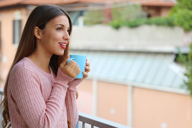 Belle fille avec pull chaud en dégustant une boisson chaude le matin