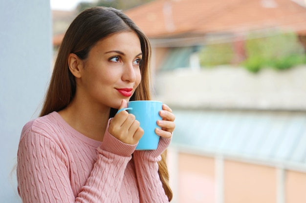 Belle fille avec pull chaud en dégustant une boisson chaude le matin