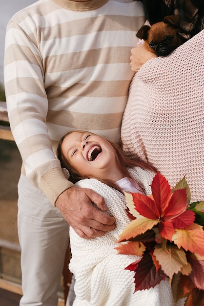 Belle fille qui rit dans les bras de sa mère et de son père