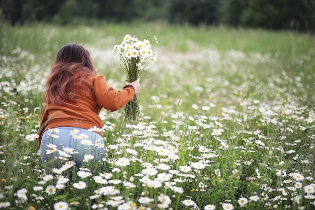 Belle fille recueille des marguerites dans le champ d'été