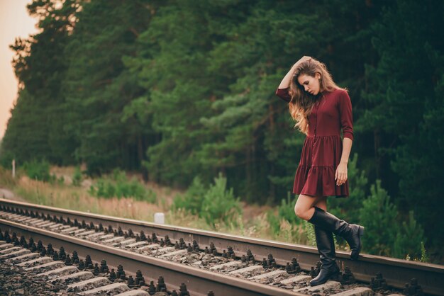 Belle fille réfléchie triste avec des cheveux naturels bouclés sur la nature dans la forêt sur le chemin de fer