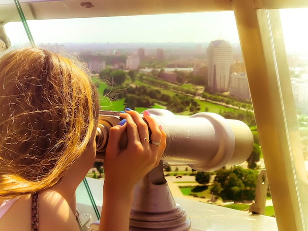 Une belle fille regarde le paysage un panorama de la ville dans la salle d'observation une paire