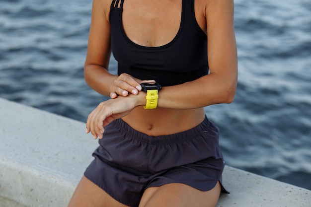 Belle fille de remise en forme porte une montre intelligente avant de courir au bord de la mer