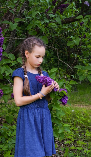 Belle fille reste avec des fleurs lilas dans la tristesse