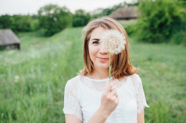 Belle fille en robe blanche se trouve dans l'herbe verte