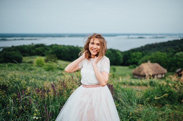 Belle fille en robe blanche se trouve dans l'herbe verte