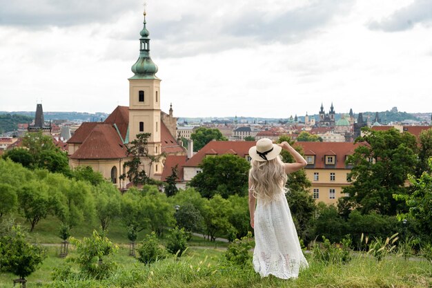 Belle fille en robe blanche voyageant dans l'église de Prague en arrière-plan