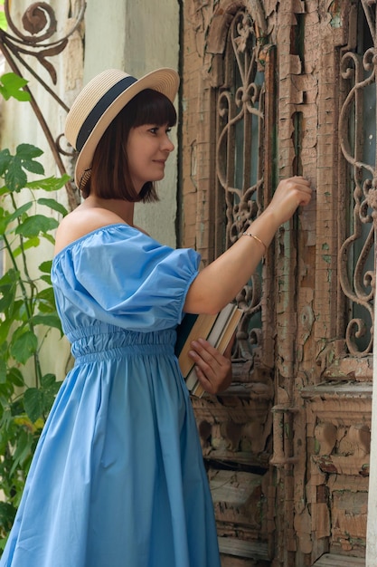 belle fille en robe bleue avec des livres près de la vieille porte