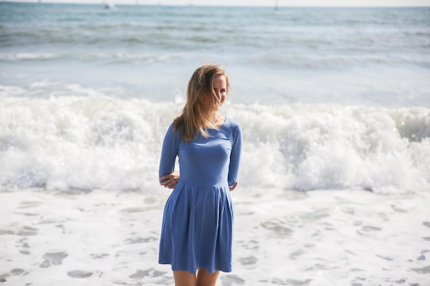 Belle fille en robe bleue marche sur la plage Incroyable photo d'été Femme près de la mer Émotions heureuses et amusantes Concept de voyage de vacances Jambes minces Eau chaude de l'océan