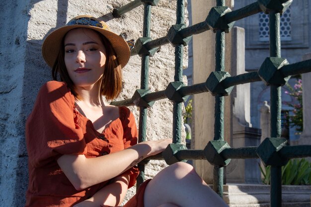 Belle fille avec une robe de couleur orange posant avec la clôture de la mosquée Suleymaniye