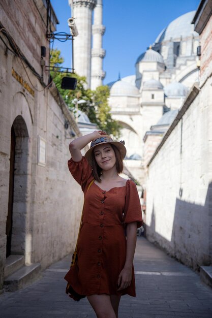 Belle fille avec une robe de couleur orange posant devant la mosquée Suleymaniye