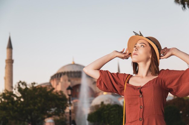 Belle fille avec une robe de couleur orange posant avec la mosquée Sultan Ahmet pendant le coucher du soleil d'Istanbul