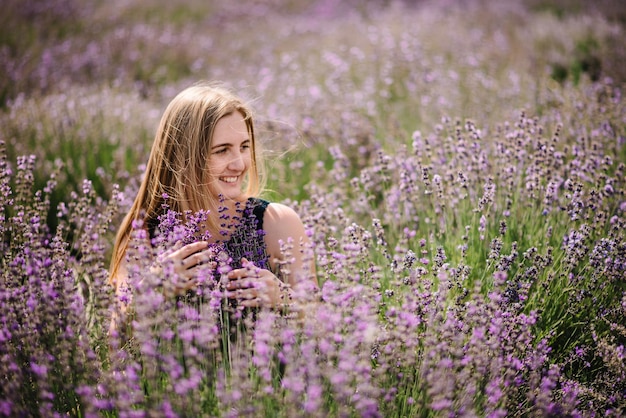 Belle fille en robe dans le champ de lavande pourpre Belle femme marche sur le champ de lavande Fille ramasse de la lavande Profitez de la nature estivale de la clairière florale Cosmétiques naturels et concept de maquillage écologique