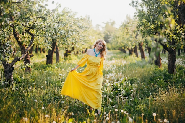 Belle fille en robe jaune dans un jardin fleuri