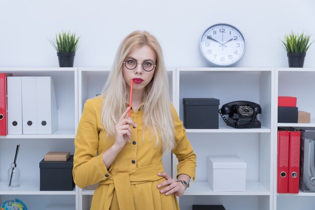 Belle fille en robe jaune posant au bureau