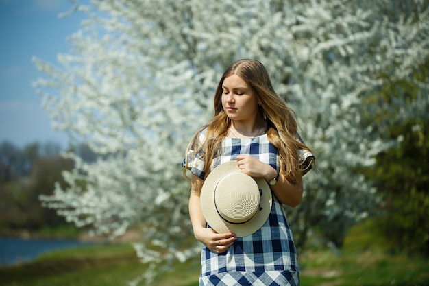 Belle fille en robe marchant dans la forêt printanière où les arbres fleurissent