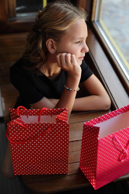 Belle fille en robe noire est assise sur un tramway avec des achats