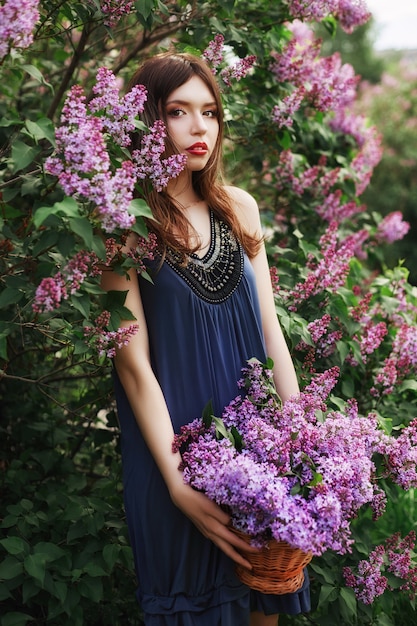 Belle fille en robe posant près de Bush de lilas