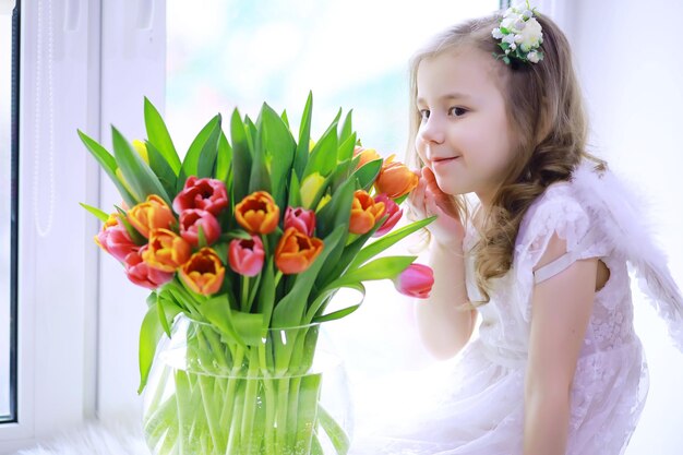 Belle fille en robes blanches avec un magnifique bouquet des premières tulipes Journée internationale de la femme Fille avec des tulipes