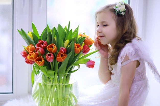 Belle fille en robes blanches avec un magnifique bouquet des premières tulipes Journée internationale de la femme Fille avec des tulipes