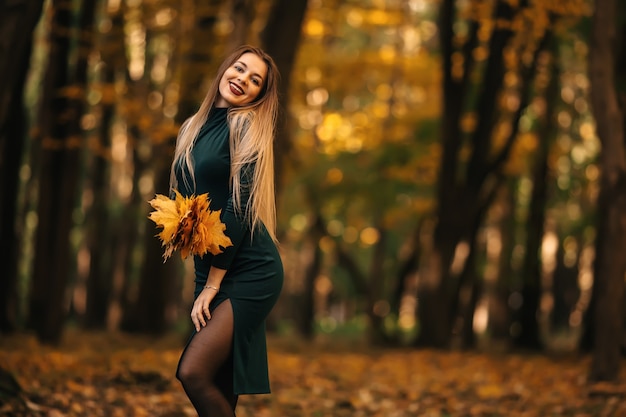 Belle fille romantique avec un bouquet de feuilles d'érable au parc d'automne