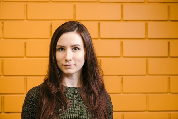 Belle fille rousse contre le mur de briques jaunes