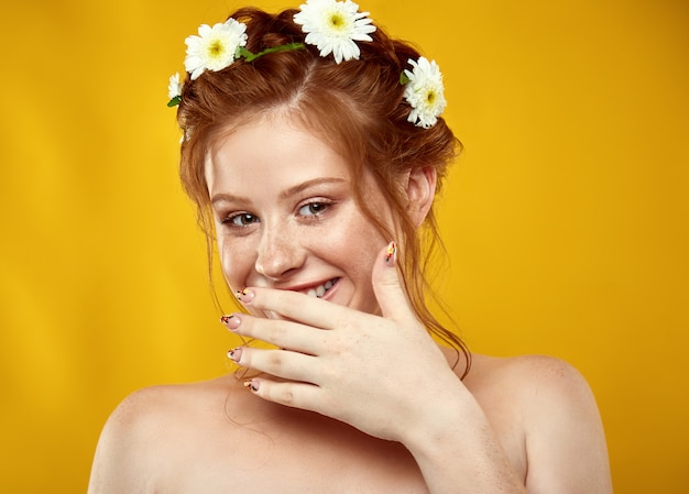 Belle fille rousse positive avec une couronne de camomille sur sa tête