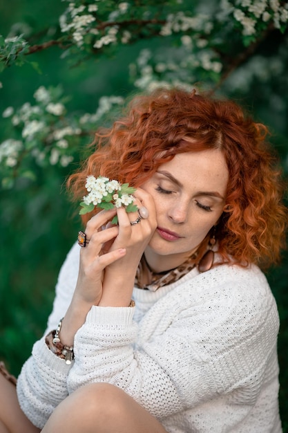 Belle fille rousse près d'un arbre en fleurs