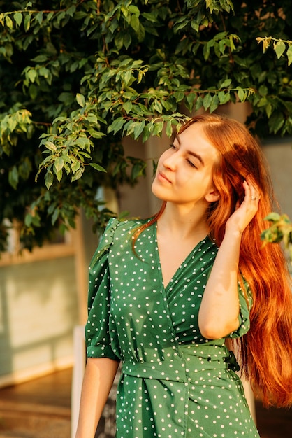 Belle fille rousse vêtue d'une robe verte lors d'une promenade dans le jardin