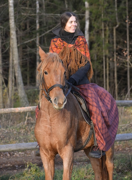 Photo belle fille russe à cheval sur le fond de la forêt.