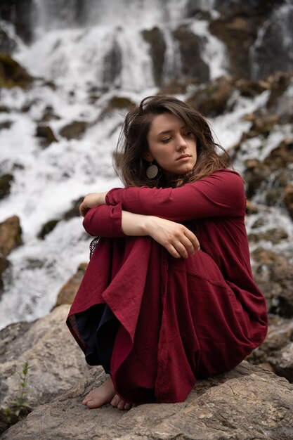 La belle fille s'assied et apprécie la vue de la cascade