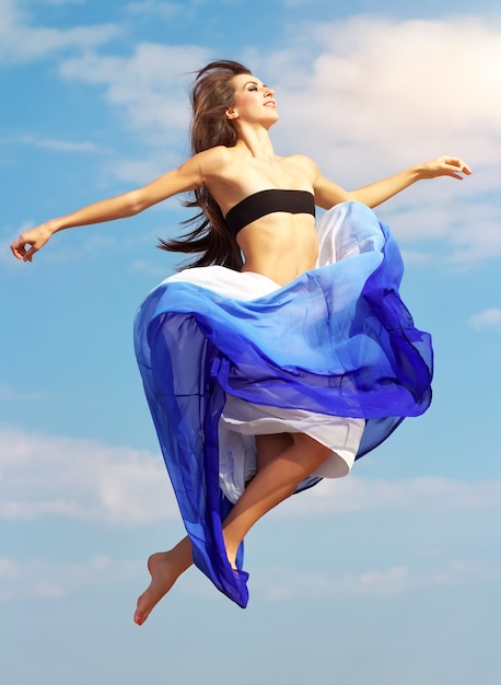 Photo belle fille sauteuse contre un ciel bleu