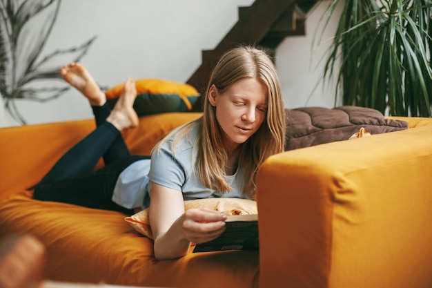 Une belle fille se détend sur le canapé dans le salon