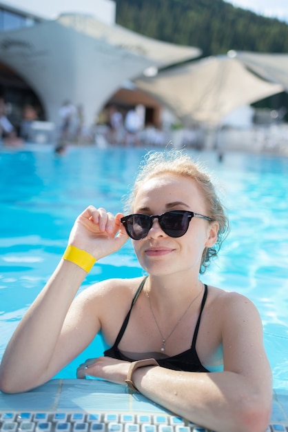 Belle fille se détend dans la piscine en journée ensoleillée