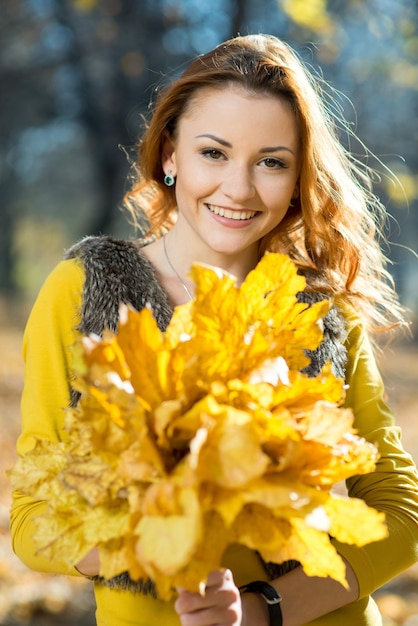 Belle fille se promène dans le parc d'automne avec des feuilles tombées jaunes