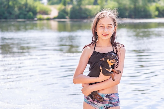 Une belle fille se tient au début de la rivière avec un chien Chihuahua. Enfant et chien. Animaux.