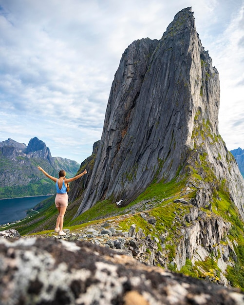 belle fille se tient sur les rochers avec ses mains en profitant de la vue sur la célèbre montagne segla