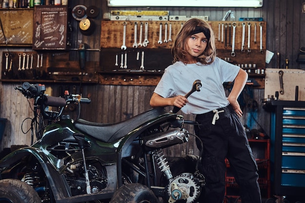 Une belle fille sérieuse veut être technicienne automobile quand elle sera grande, elle essaie de réparer un VTT cassé.