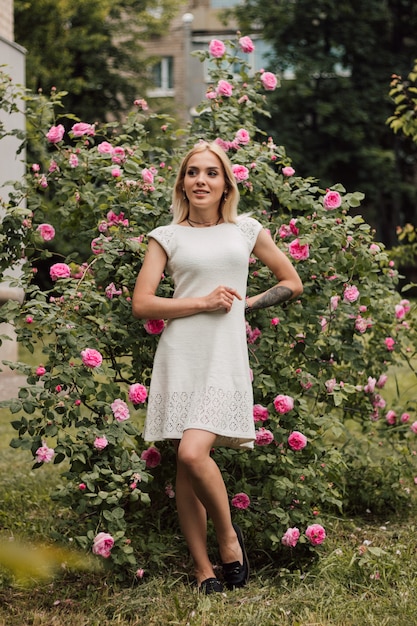 Belle fille sexy en blanc tricoté sur un fond de nature et de roses en fleurs