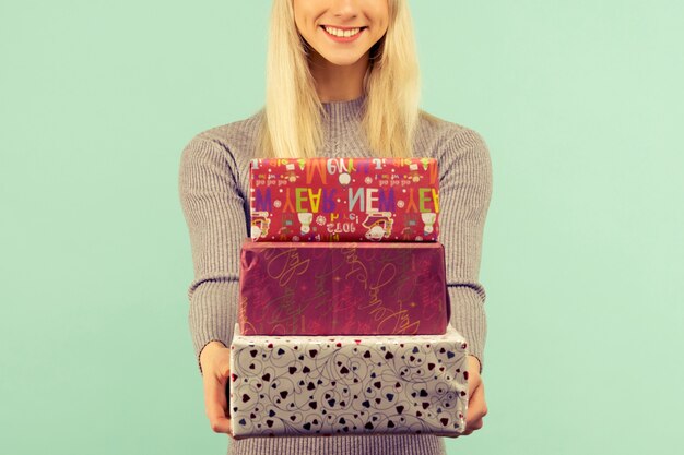 Une belle fille sexy dans un chapeau du Nouvel An et une robe grise, tient dans les mains des cadeaux. Célébration de Noël ou du nouvel an