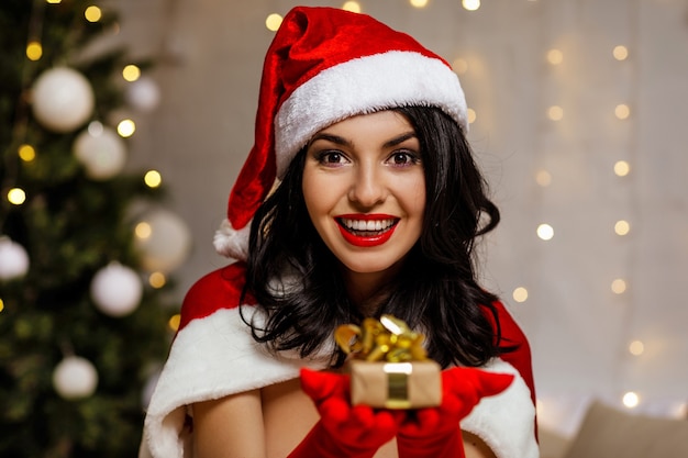 Belle fille sexy portant des vêtements de père Noël avec boîte-cadeau de Noël