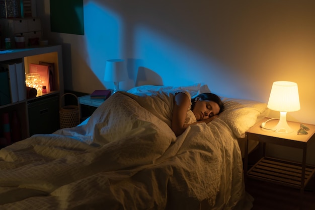 Belle fille souffrant d'insomnie allongée dans son lit avec les couleurs bleues de la lune