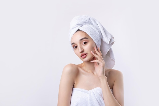 Belle fille avec des sourcils épais et une peau parfaite à la serviette de fond blanc sur la photo de beauté de la tête