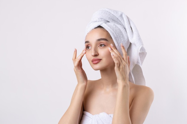 Belle fille avec des sourcils épais et une peau parfaite à la serviette de fond blanc sur la photo de beauté de la tête