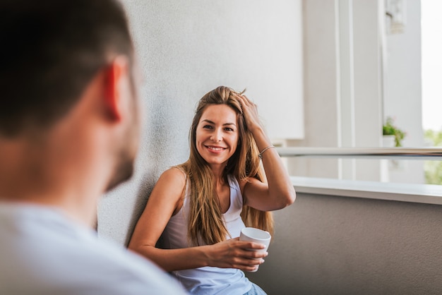 Belle fille souriante assise sur le balcon avec son petit ami.