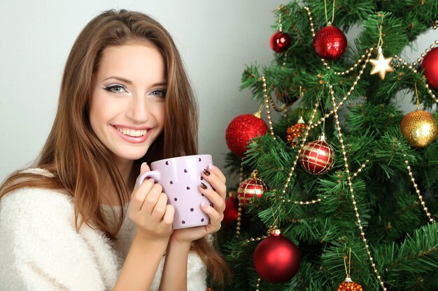 Belle fille souriante assise près de l'arbre de Noël