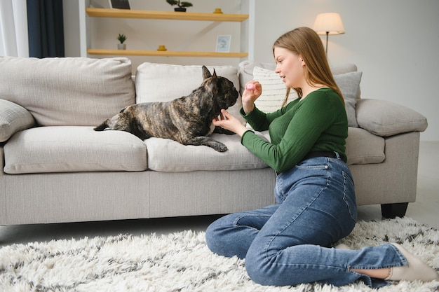 Belle fille souriante et assise sur le sol près du bouledogue français