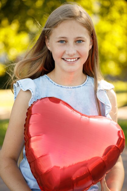 Belle fille souriante avec ballon coeur