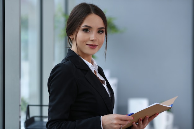 Belle fille souriante de commis portant costume tenir cahier