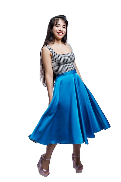 Une belle fille souriante dans une jupe volante bleue et des talons hauts Positivité et joie Isolé sur fond blanc Vertical
